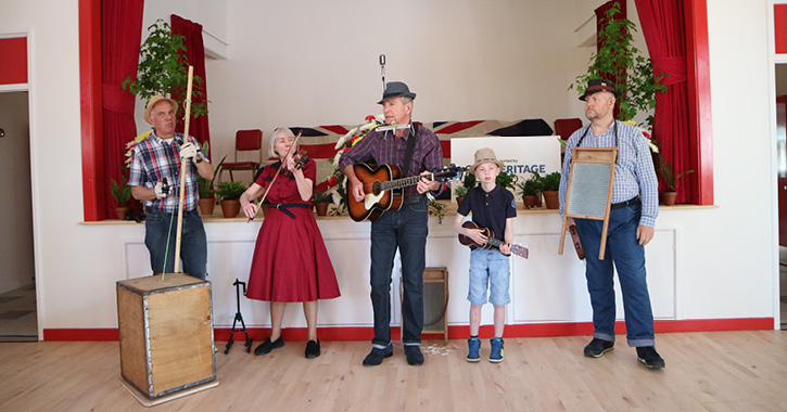 Skiffle music band stood with instruments inside in the 1950s Welfare Hall at Beamish Museum